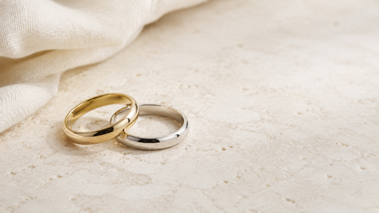 Dos alianzas de boda en oro amarillo y oro blanco sobre piedra clara