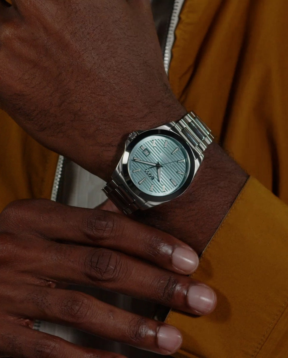 Reloj Hugo Boss en muñeca masculina, caja redonda, esfera azul, estilo moderno y elegante, diseño de tres agujas.